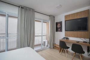 um quarto de hotel com uma cama e uma secretária com uma televisão em MOL - Liberdade - Anora Spaces Residenciais em São Paulo