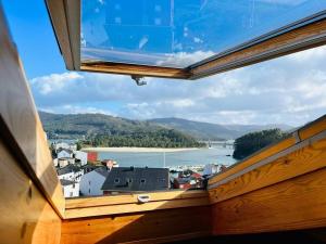 una ventana con vistas a la ciudad y al agua en Ático completo de 3 habitaciones en O Barqueiro en O Barqueiro