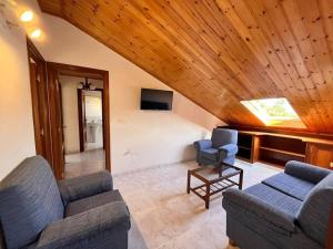 sala de estar con 2 sofás azules y techo de madera en Ático completo de 3 habitaciones en O Barqueiro en O Barqueiro