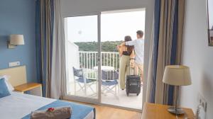 - un couple debout sur le balcon d'une chambre d'hôtel dans l'établissement Seth Playa Azul, à Cala'n Porter