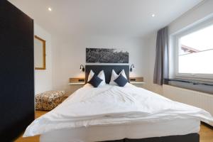 1 cama blanca grande en un dormitorio con ventana en Appart-Pension Schnöll, en Mittersill