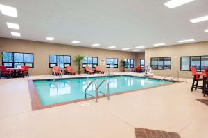 una piscina en una habitación de hotel con sillas y mesas rojas en Hampton Inn Columbus/Taylorsville, en Edinburgh