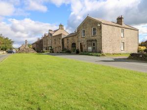 a large brick building with a green lawn in front of it at Hall Garth Cottage in Leyburn