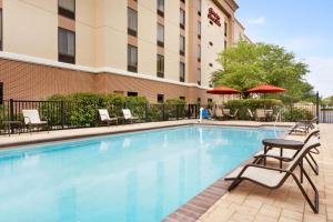 a swimming pool at a hotel with chairs and umbrellas at Hampton Inn & Suites Largo in Largo
