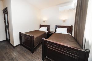 two beds in a small room with two beds at Dvin Hotel in Pavlodar