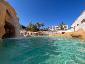 Azure Retreat - Private Luxury Sea View Apartment في شرم الشيخ: مسبح في منتجع ماء ازرق واضح