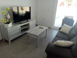 sala de estar con TV, sofá y mesa en Villa María en Alicante