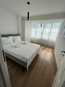 a white bedroom with a bed and a wooden floor at Lovely Cozy Apartments in Central Suceava in Suceava