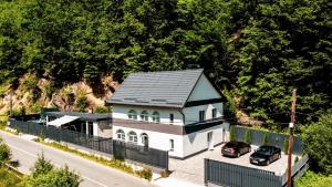 una casa con dos coches estacionados frente a ella en TRANSILVANIA BLISS COTTAGE, en Someşu Rece