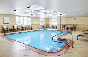 una piscina en una habitación de hotel con sillas y mesas en Homewood Suites Champaign-Urbana en Champaign