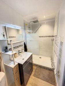 uma casa de banho branca com um chuveiro e um lavatório. em Les pénates du pastel - Jardin & Terrasse em Villefranche-de-Lauragais