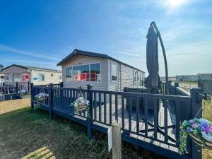 a tiny house with an umbrella on a deck at Lovely Caravan With Decking Free Wifi At North Denes Caravan Park Ref 40145nd in Lowestoft