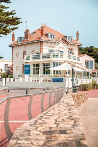 a large building with a tennis court in front of it at Hôtel de charme & SPA Le Grand Large in La Bernerie-en-Retz