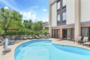 a swimming pool with chairs and a building at Hampton Inn Commerce in Commerce