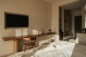 a bedroom with a bed and a desk with a television at AMÉNTE Mindful Stay in Plakias