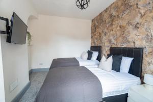 a bedroom with a large bed with a stone wall at Stylish 3 Bedroom House - Central Location in Nottingham