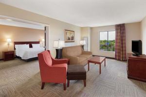 a hotel room with a bed and a couch and chairs at Hampton Inn Columbus-North in Columbus