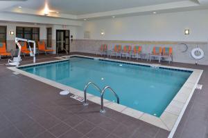 a large swimming pool with orange chairs around it at Hilton Garden Inn West Chester in West Chester