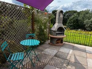 a patio with a stove and two chairs and a table at Silver Springs Farm Lodge in Dingestow