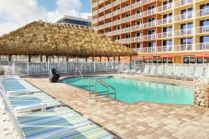 ein Pool mit Stühlen und ein großes Gebäude in der Unterkunft Hampton Inn Daytona Beach/Beachfront in Daytona Beach