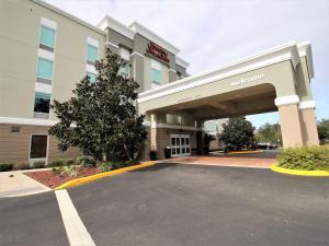 Hampton Inn & Suites Palm Coast في فلاغلار بيتش: اطلالة على مبنى الفندق مع موقف للسيارة