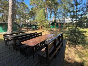 une table en bois et des bancs sur une terrasse avec une aire de jeux dans l'établissement Domki letniskowe Delfin, à Mrzeżyno