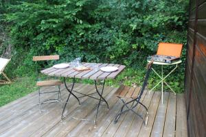 a table and two chairs and a grill on a deck at LES GRANGES D'ANTAN - le REFUGE FORESTIER - INSOLITE SANS EAU - ELECTRICITE AVEC BATTERIE NOMADE in Chalonnes-sous-le-Lude +12 photos