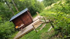 a small wooden cabin with a blue roof at LES GRANGES D'ANTAN - le REFUGE FORESTIER - INSOLITE SANS EAU - ELECTRICITE AVEC BATTERIE NOMADE in Chalonnes-sous-le-Lude
