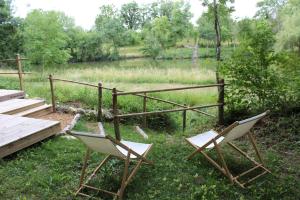 two chairs sitting next to a table and a fence at LES GRANGES D'ANTAN - le REFUGE FORESTIER - INSOLITE SANS EAU - ELECTRICITE AVEC BATTERIE NOMADE in Chalonnes-sous-le-Lude