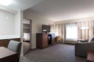 a hotel room with a television and a room with a bed at Hampton Inn & Suites Dallas DFW Airport North Grapevine in Grapevine