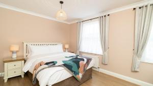 a bedroom with a bed and two windows at Lamington Apartments - Hammersmith in London