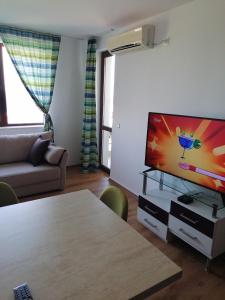 a living room with a flat screen tv and a table at Апартамент в Бяла in Byala