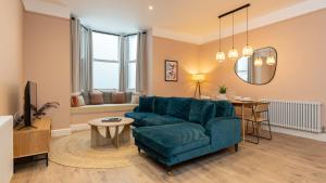 ロンドンにあるLamington Apartments - Hammersmithのリビングルーム(青いソファ、テーブル付)