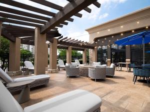 an outdoor patio with chairs and tables and umbrellas at Hampton Inn & Suites Dallas-DFW Airport Hurst in Hurst