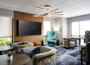 a waiting room with chairs tables and a flat screen tv at Hampton Inn & Suites Dallas-DFW Airport Hurst in Hurst