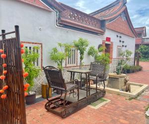 a patio with two chairs and a table in front of a building at 新龍頭古厝行館 Shin Long Tou B&B in Jinning