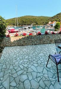 a stone patio with a chair and a wall at Guesthouse Porto in Cres