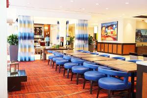 Hilton Garden Inn Falls Church في فولز تشيرش: طاولة طويلة وكراسي زرقاء في مطعم