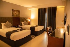 塞拉莱Tulip Inn Majan Hotel and Suites Salalah的有两张床和一扇窗户的酒店房间