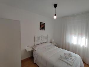 a white bedroom with a white bed and a window at Casa El Carmen in Alar del Rey