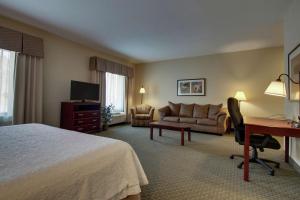 a hotel room with a bed and a desk and a couch at Hampton Inn & Suites Denver Littleton in Littleton