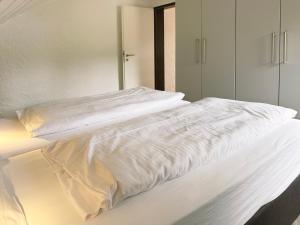 Una cama con sábanas blancas encima. en Ferienpark Rursee, en Simmerath