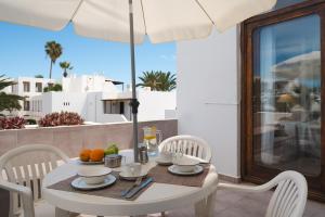 a white table with chairs and an umbrella on a balcony at Lanzarote Beach Apartments, CASA ONA in Costa Teguise