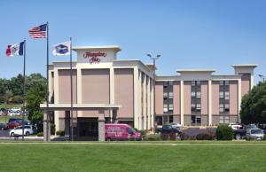 a building with a car parked in a parking lot at Hampton Inn Des Moines-Airport in Des Moines