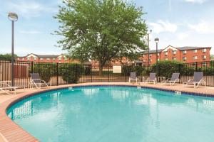 a swimming pool with chairs and a tree and buildings at Hampton Inn Des Moines-Airport in Des Moines