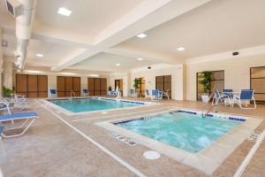 uma piscina num quarto de hotel com cadeiras e mesas em Hampton Inn & Suites Detroit/Chesterfield em Chesterfield