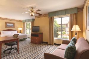 a hotel room with a bed and a couch and a tv at Homewood Suites by Hilton Detroit-Troy in Birmingham