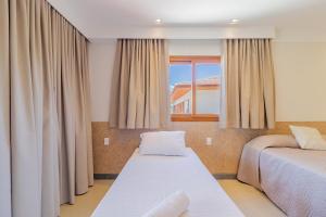 a bedroom with two beds and a window at PF55 Ótima Casa 4 Suítes - Praia do Forte in Farol +56 photos