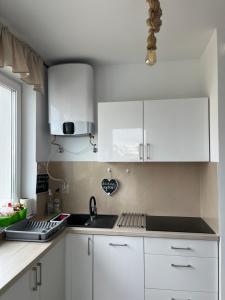 een keuken met witte kasten en een wastafel bij Willa Koralowa 16 - BASEN PODGRZEWANY, KLIMATYZACJA in Sarbinowo