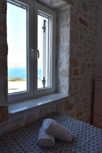 a bedroom with a window with a towel on a bed at Sea View Stone House in Naousa +6 photos